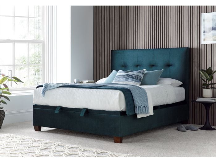 Luxurious deep blue velvet ottoman bed frame with modern dark wooden feet.